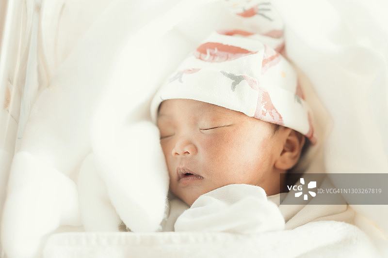 在新生儿床上睡觉的可爱亚洲新生儿图片素材