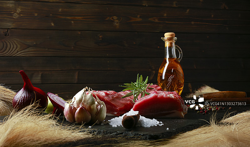 带有大蒜、迷迭香、洋葱盐、胡椒粉和橄榄油的黑盘生野猪肉细节照片图片素材