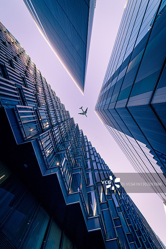 仰望伦敦的现代企业建筑，商用飞机飞过图片素材