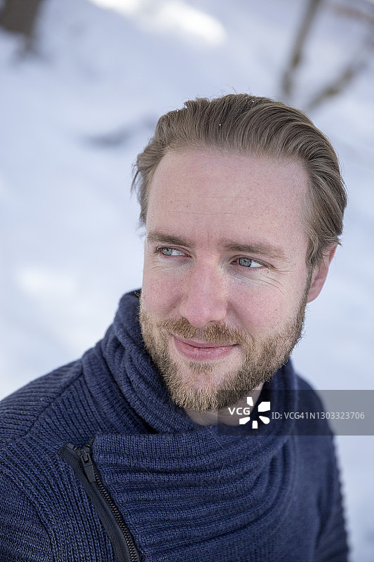 在雪地里，蓝眼睛的英俊年轻男子看向远方图片素材