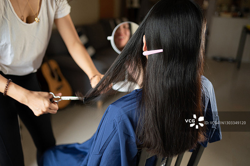 女人在阳台旁的客厅里为朋友剪发图片素材