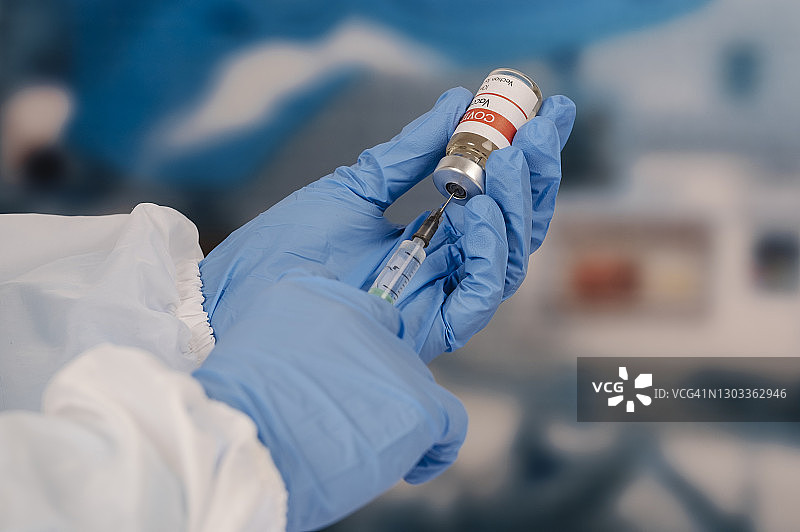 戴着蓝色防护手套的年轻护士拿着医用注射器和小瓶图片素材