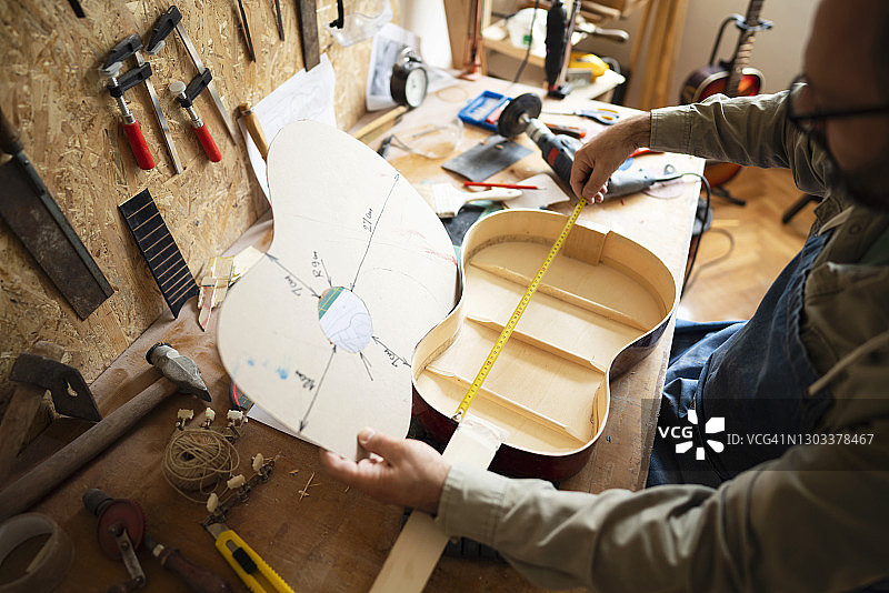 工匠测量吉他并与蓝图进行比较图片素材