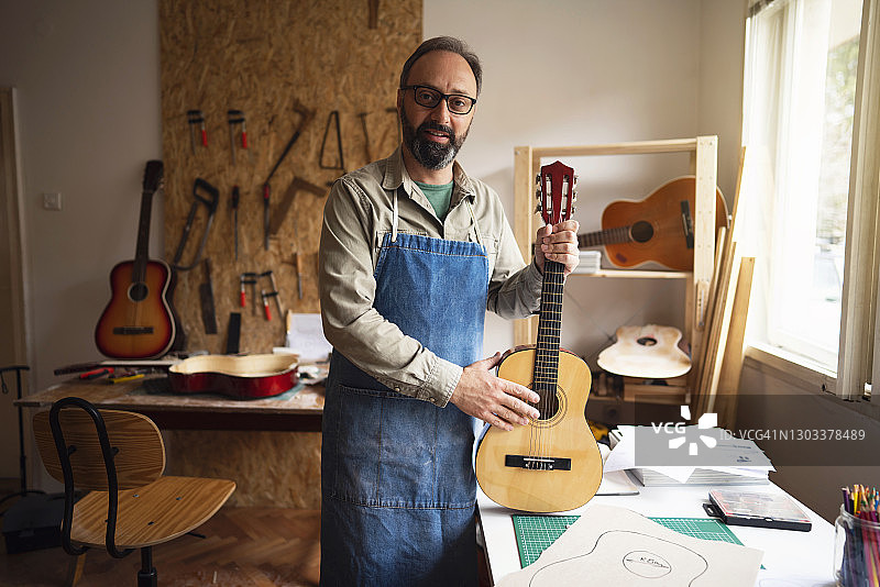 修理完古典吉他后快乐的工匠肖像图片素材