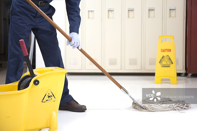 在办公楼里拖地的年长清洁工（戴防护口罩）图片素材