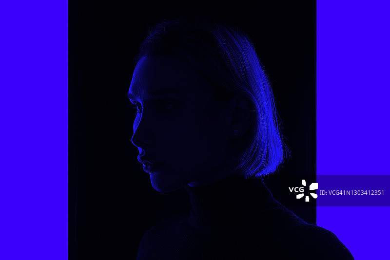 年轻女子站在蓝色发光背景中的轮廓图片素材