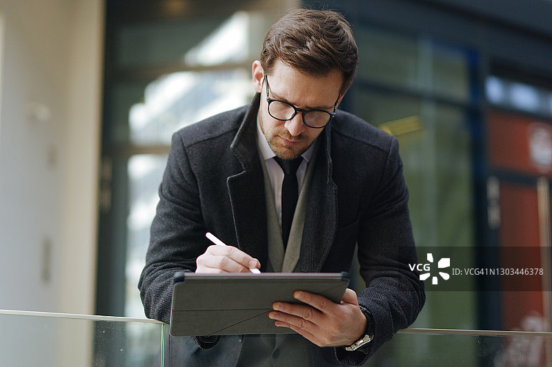 一位英俊的年轻主管在户外使用他的数码平板电脑工作图片素材