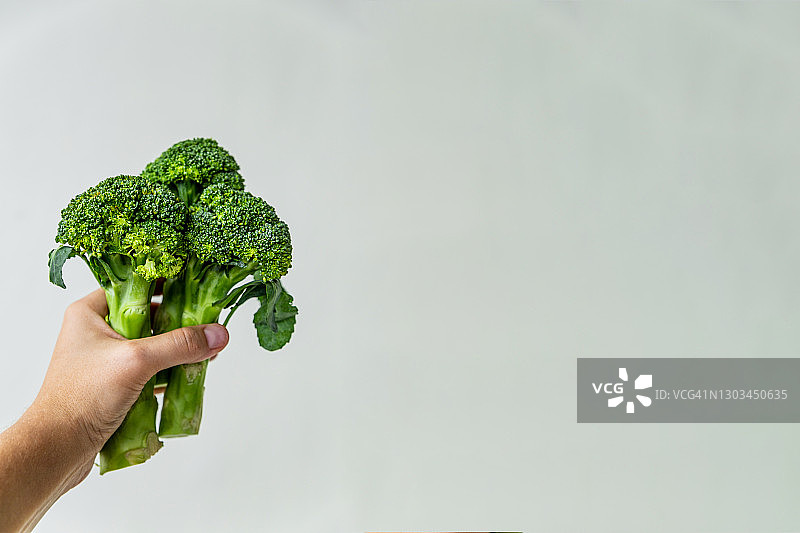 灰色背景上手持的新鲜西兰花，特写，留白图片素材