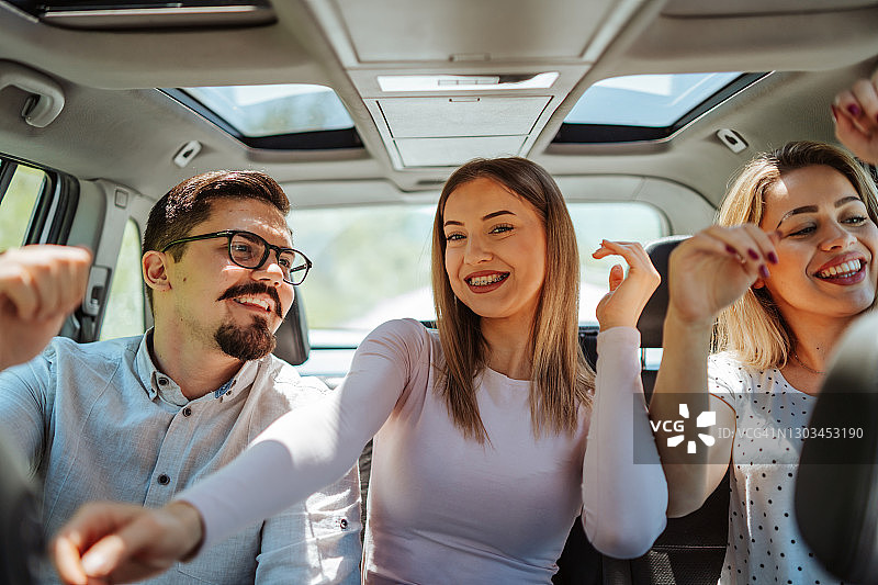 朋友们在汽车后座上快乐玩耍图片素材