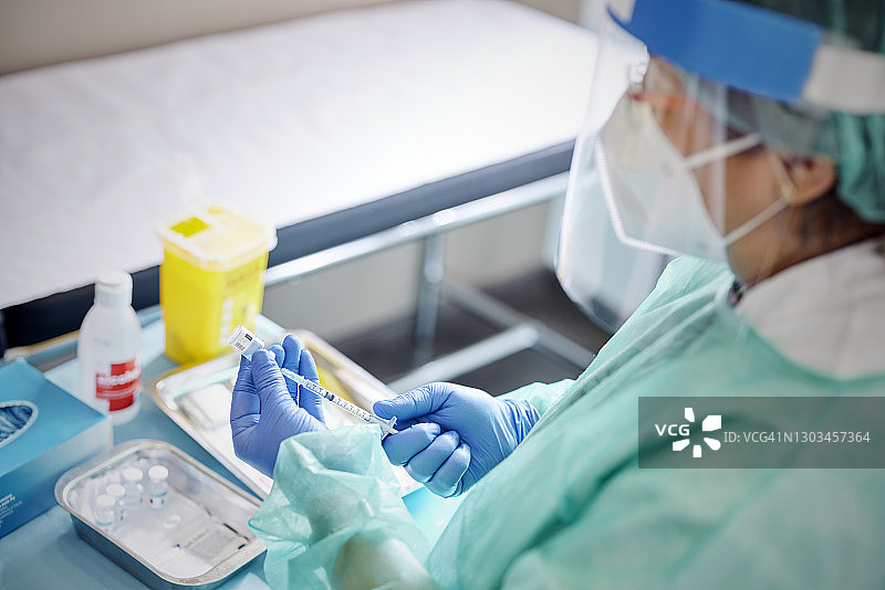 戴防护面罩、FPP2口罩和手套的混血女护士准备新冠疫苗接种图片素材