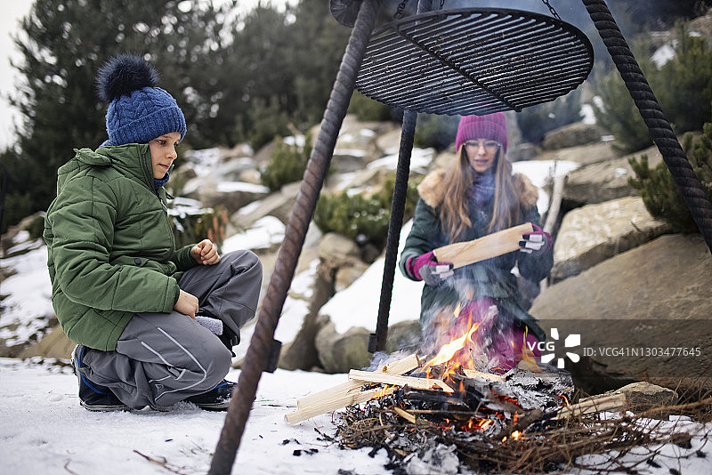 哥哥和妹妹在后院照看烧烤架下的火图片素材