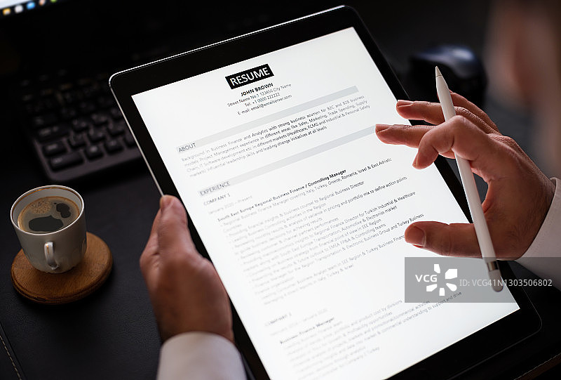 商人阅读平板电脑上的简历以招聘合适人选图片素材
