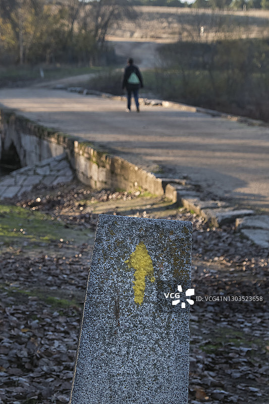 马德里圣地亚哥之路的黄色箭头，在巴利亚多利德省阿达哈河上的石桥上，西班牙卡斯蒂利亚和莱昂图片素材