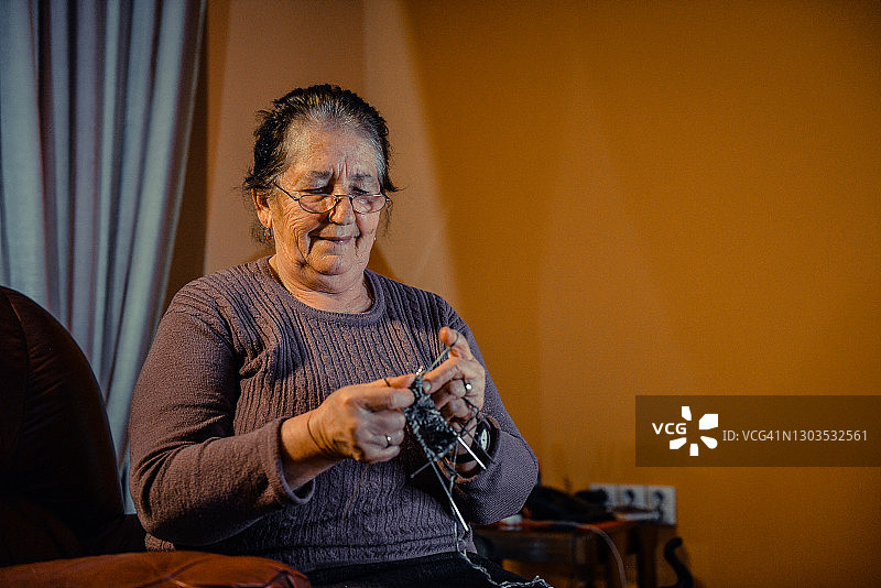 坐在沙发上编织的年长女性图片素材