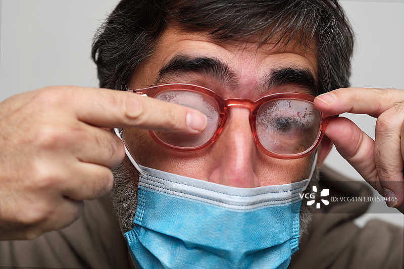 一个男人用手指清洁眼镜，被雾气遮挡视线图片素材