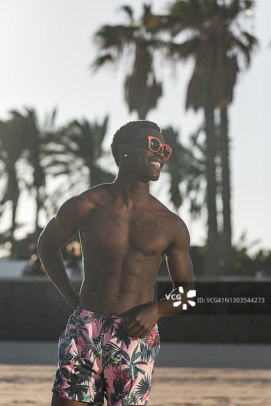穿着夏装享受热带海滩的快乐黑人男子图片素材