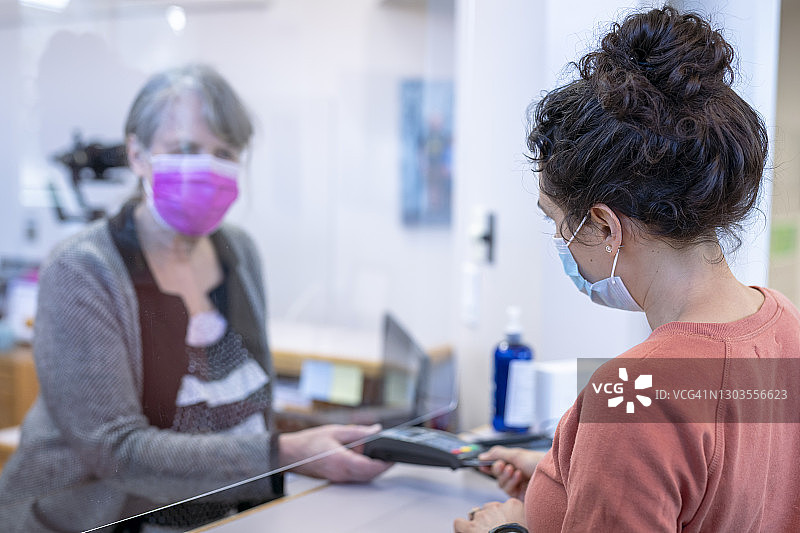 混血女患者在牙科诊所支付医疗费用图片素材