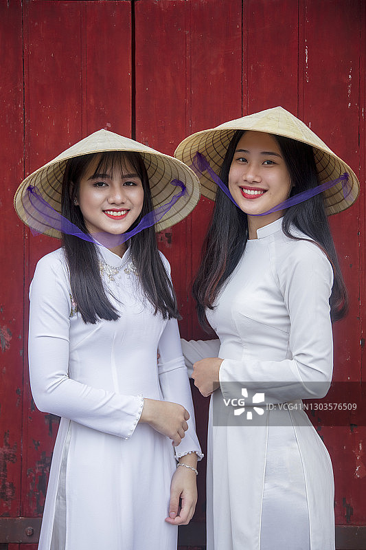 身穿传统服饰的两位年轻女人站在越南顺化紫禁城的西门图片素材
