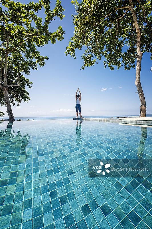 在印度尼西亚海边的无边泳池边做瑜伽的亚洲女性图片素材