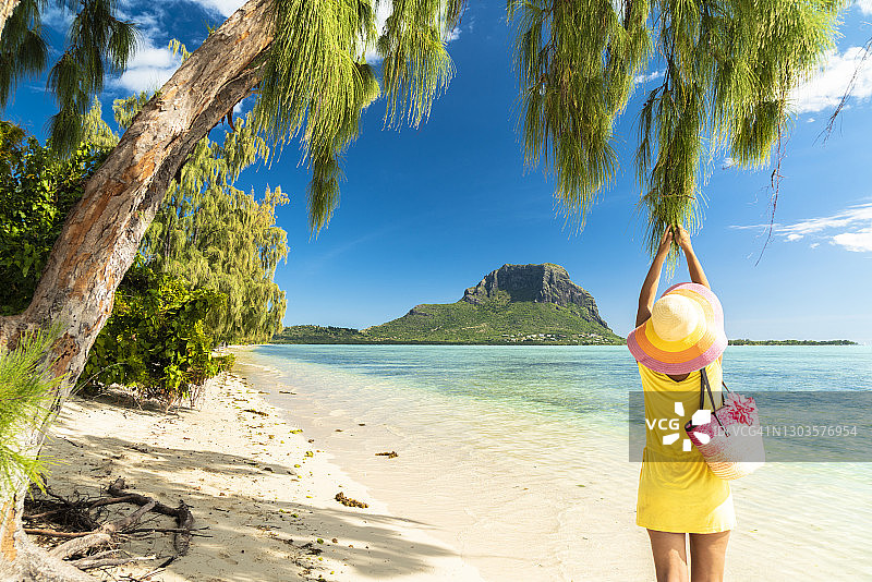 女子在毛里求斯贝尼蒂耶岛沙滩的热带树下玩耍图片素材