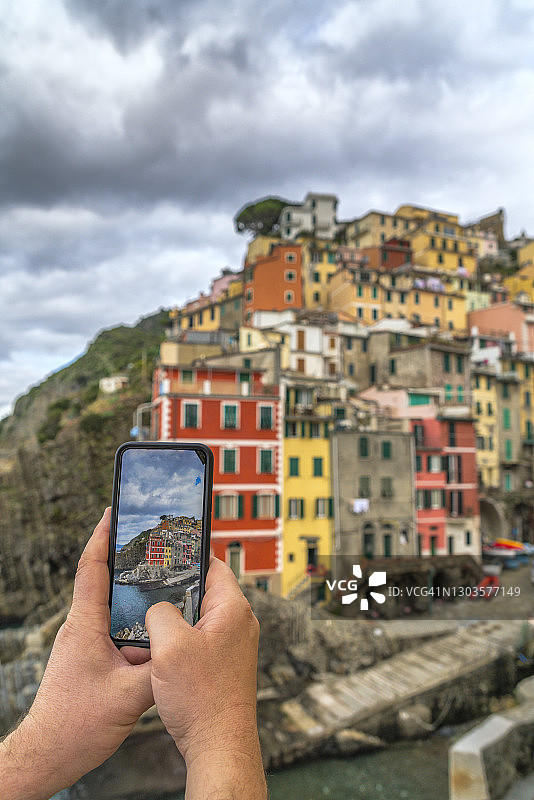 男子用手机拍摄意大利五渔村里奥马焦雷图片素材