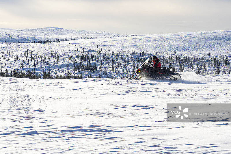 男士在芬兰拉普兰萨利色尔卡的雪景中驾驶雪地摩托图片素材