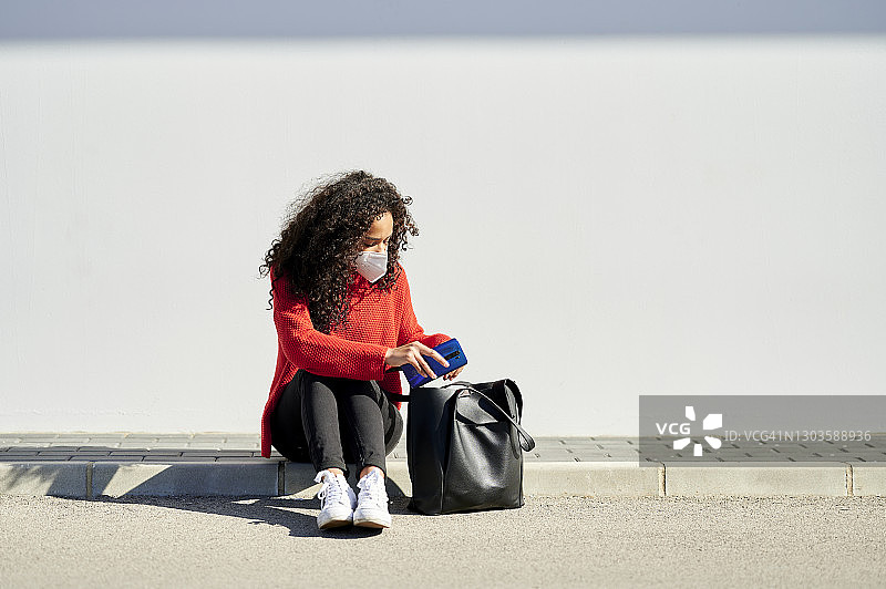 戴口罩的女人在户外查看包里的物品图片素材