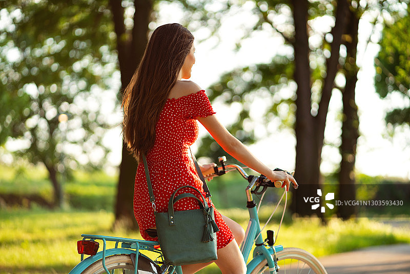 年轻女子在公园里骑自行车微笑图片素材