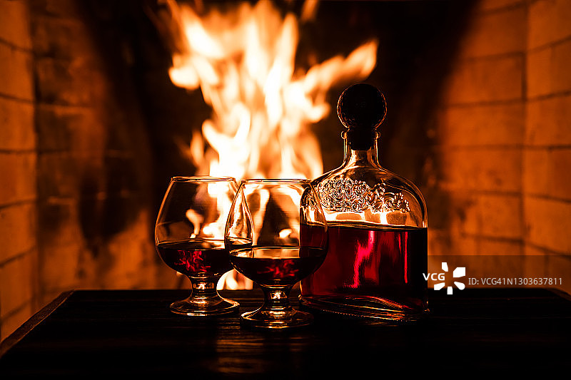 壁炉旁的两杯干邑和一瓶酒，舒适的夜晚图片素材