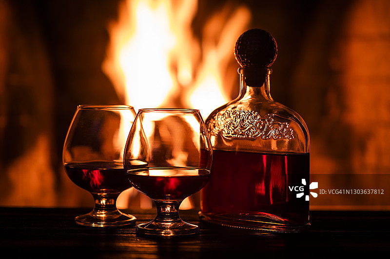 壁炉旁的两杯干邑和一瓶酒，舒适的夜晚图片素材