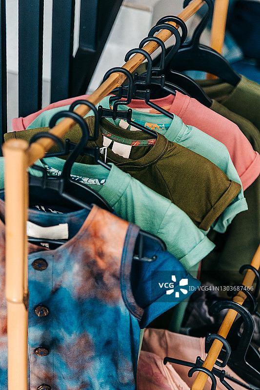 挂在衣架上的彩色T恤，高角度视图。特写，留白。折扣、销售、购物、存储概念。图片素材