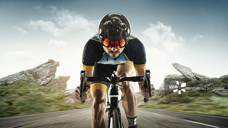 在山地背景下训练的铁人三项男运动员。 一名白人铁人三项运动员正在练习自行车，身穿运动装备图片素材