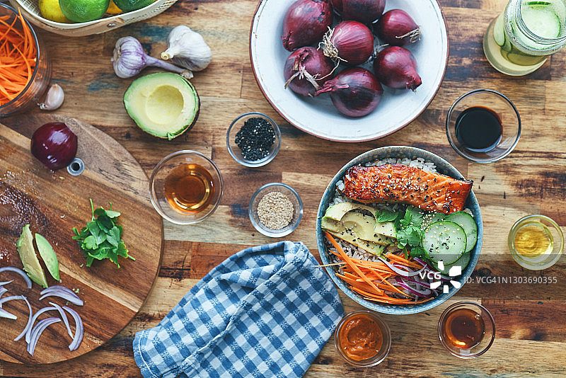 准备香辣三文鱼饭碗配米饭、胡萝卜、黄瓜和鳄梨图片素材