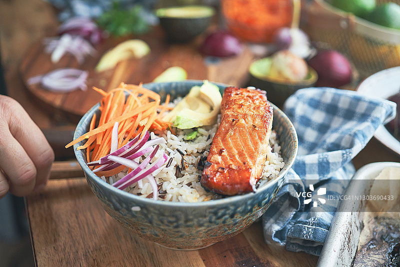 准备香辣三文鱼饭碗配米饭、胡萝卜、黄瓜和鳄梨图片素材