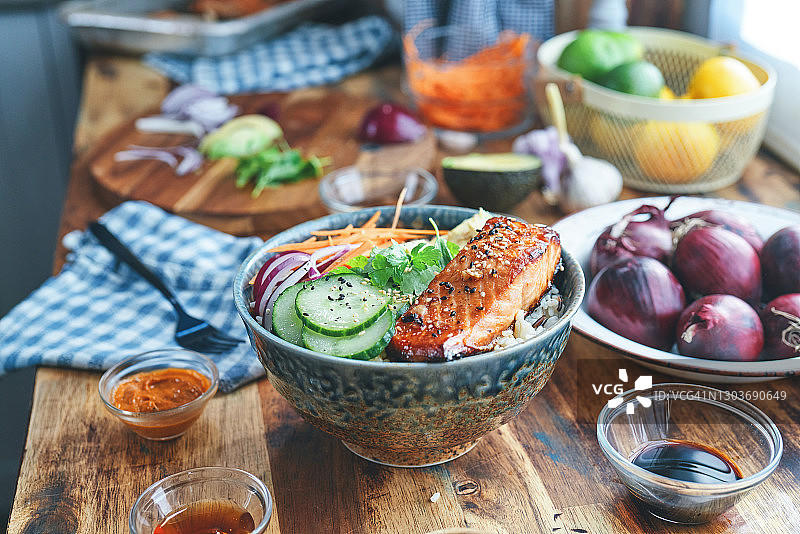 准备香辣三文鱼饭碗配米饭、胡萝卜、黄瓜和鳄梨图片素材