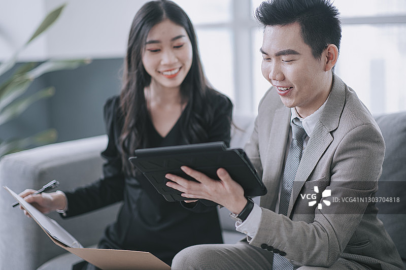 两名中国亚洲白领在商务休息室的工作站进行讨论图片素材