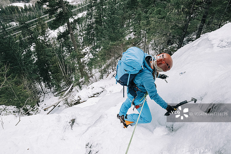 攀冰女性在冰冻瀑布中安装冰锥图片素材