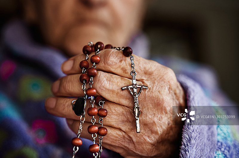 拿着念珠和十字架的年长的白人手图片素材