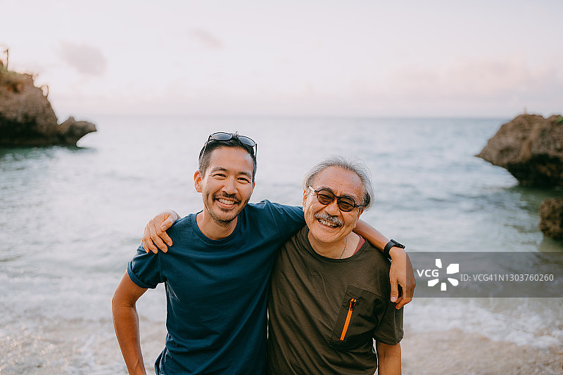 年长的父亲和成年的儿子在日落时在海滩上玩得很开心图片素材