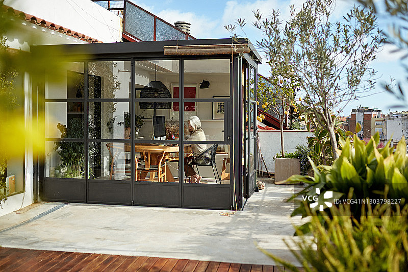 在阳光房公寓居家办公的老年妇女图片素材