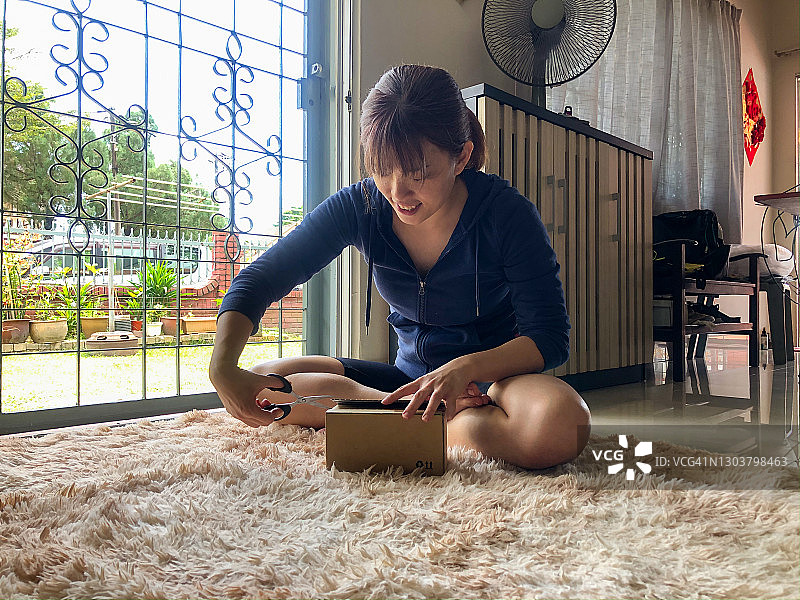 亚洲年轻女子打开网上订购的包裹图片素材