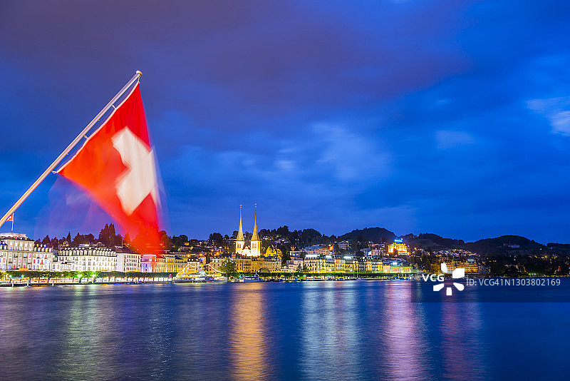 琉森湖与蓝色时分的城市风光和瑞士国旗图片素材