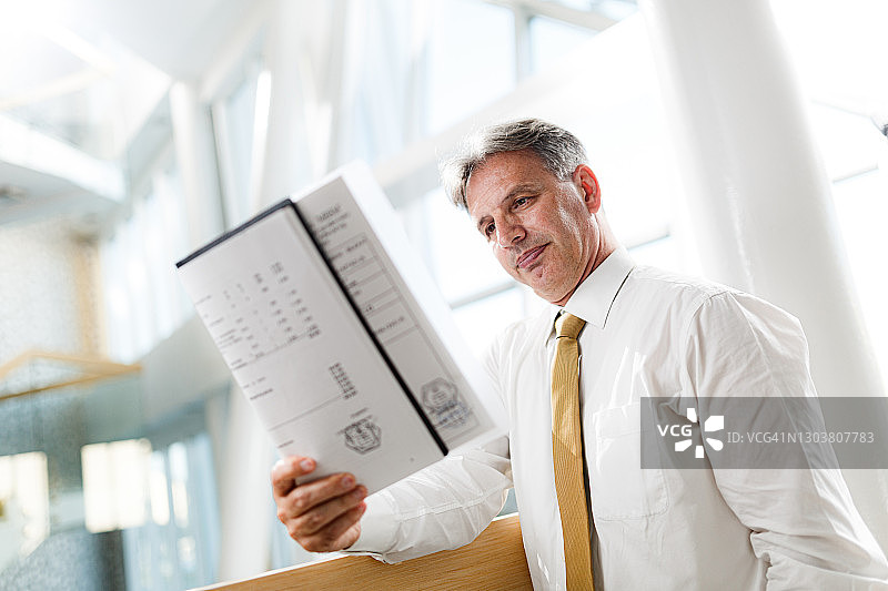 走廊里阅读报告的中年经理图片素材