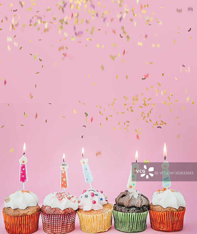 粉色背景燃烧蜡烛生日纸杯蛋糕图片素材