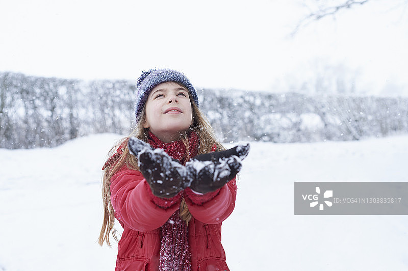 在雪景中，一个年轻女孩正在捕捉雪花图片素材