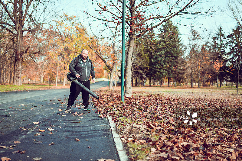 男子清理公园中的秋叶图片素材