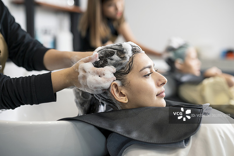 年轻女人在美容院享受美发师洗发服务，头发护理图片素材