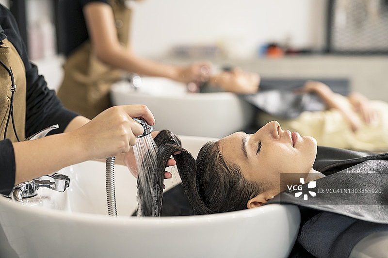 美发沙龙发型师为女性顾客洗头图片素材