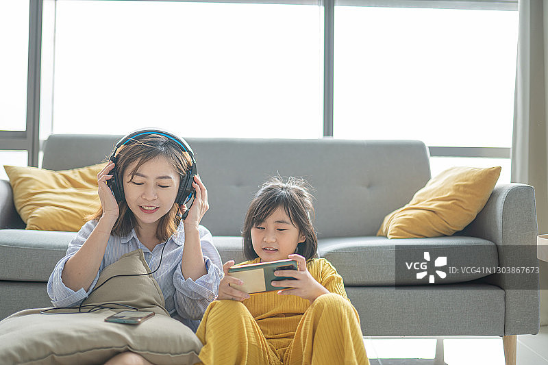 中国母女在客厅用手机耳机听音乐图片素材