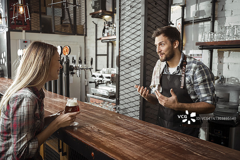 年轻调酒师在酒吧与女顾客交谈图片素材